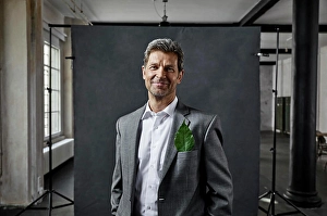 Sustainable Energy Prints: Portrait of mature businessman with leaf in pocket in front of black backdrop in loft