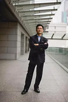 Out Door Prints: Portrait of a mid-adult businessman standing with his arms crossed in the city