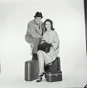 Trench Prints: Portrait of a mid adult couple sitting with luggage