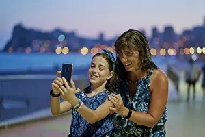 Texting Prints: Portrait of mother and teenage daughter wearing blue dresses