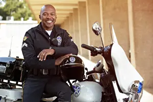 Bald Prints: Portrait of Police officer sitting on his motorcycle outside looking towards camera smiling