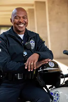 Bald Prints: Portrait of Police officer sitting on his motorcycle outside looking towards camera smiling
