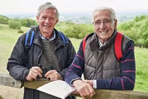 Hike Prints: Portrait Of Two Retired Male Friends On Walking Holiday Resting On Gate With Map