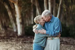 Grandma Prints: Portrait of senior adult retired couple kissing in forest