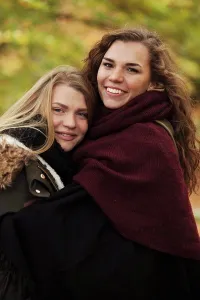 Vertically Prints: Portrait of sisters embracing outdoors