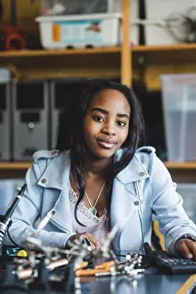 Innovation Prints: Portrait of smiling female high school student sitting with science project at desk in classroom