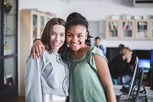 Highschool Student Prints: Portrait of smiling female teenage friends standing with arm around in computer lab at high school