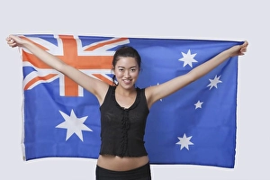 Patriotic Prints: Portrait of smiling young woman holding Australian flag over white background