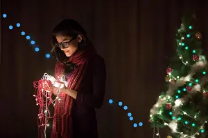 Festive Prints: Portrait of a woman holding fairy lights during Christmas celebration