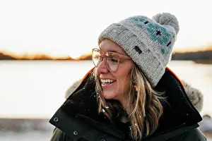 Festive Prints: portrait of woman smiling with snow in her hair at sunset