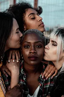 Diverse Prints: Portrait of young black short haired woman looking at camera with serious face while female friends supporting with
