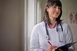 Doctors Prints: Portrait of a young female doctor holding a clipboard in her office