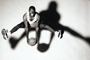 Sseditor Aa Prints: Portrait of a young man holding a basketball jumping up in the air