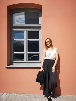 Individuality Prints: Portrait of a young smiling businesswoman opposite the orange wall and window