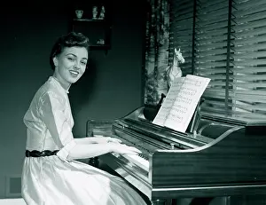 Arts Culture And Entertainment Prints: Portrait of young woman playing piano at home