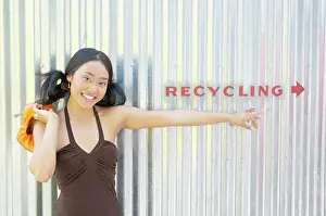 Medium Length Prints: Portrait of a young woman standing against a corrugated metal wall smiling