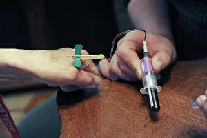 Report Prints: Private nurse performs a blood test at home in an elderly person