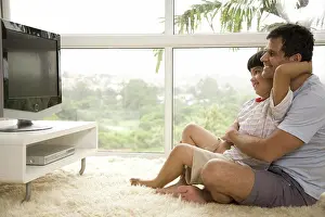 Away Prints: Side profile of a mature man with his son watching television