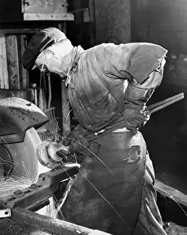 Manual Worker Prints: Side profile of a senior man working on a machine in a factory