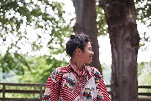 Kindness Prints: Profile of smiling non-binary adult in colourful shirt in forrest