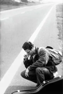 Instrument Prints: Side profile of a young man squatting on the road smoking a cigarette