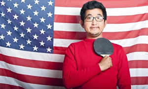 Paddle Prints: Proud Asian Man holding table tennis paddle against US Flag