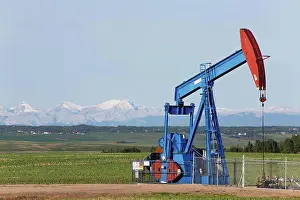 Resource Prints: A Pumpjack In A Field With The Rocky Mountains In The Distance; Alberta, Canada