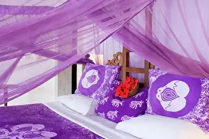 Textile Prints: Purple mosquito netting and hibiscus flowers on a bed at the Shooting Star Hotel