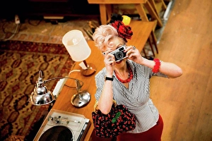Upper Body Prints: Quirky woman taking photographs on vintage camera in antiques emporium