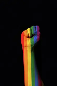 Brazil Prints: Raised fist colored with the rainbow gay pride on a dark backgro