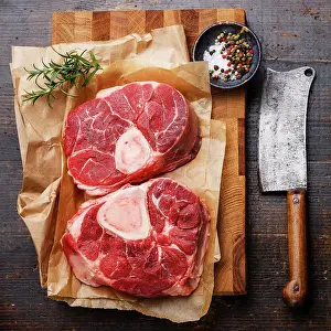 Knife Prints: Raw fresh cross cut veal shank and seasonings for making Osso Buco on wooden cutting board with meat cleaver