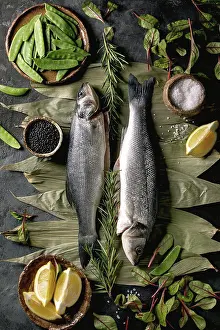 Seafood Prints: Raw fresh uncooked fish sea bass on dry bamboo leaves ready to cook with lemon