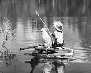 One Child Only Prints: Rear view of a boy sitting with his dog and fishing in a lake