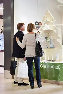 Vertically Prints: Rear view of senior couple with shopping bags looking in store window