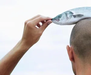 Swimming Animal Prints: Rear view of a young man with a dead fish on his head