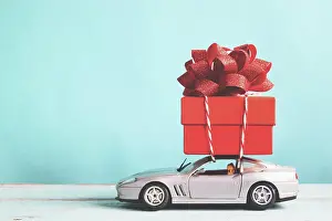 Greeting Prints: Red gift box on car toy with blue pastel color background, retro filter effect