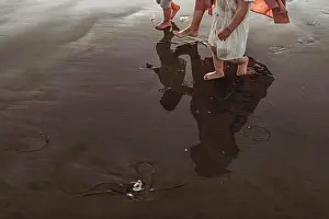 Foot Prints: Reflection in ocean water of mother walking two daughters at beach