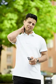 Descent Prints: Relaxed Afghan man in a white shirt smiling while holding glasses in an outdoor setting
