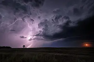 Shannon Prints: A rising moon and a storm with lightning striking over field in rural North Dakota United States