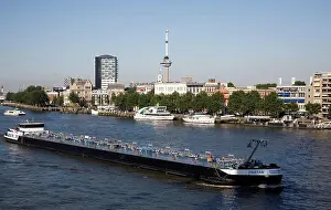 Trade Prints: River barge chemical transporter ship Tristan passing Euromast in the city