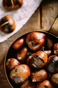 Roasted Prints: Roasted chestnuts on copper saucepan with dark wooden background