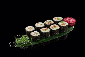 Vegetables Prints: Rolls unagi maki on bamboo leaf on black background