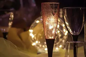 Occasion Prints: Romantic atmosphere created by a champagne flute and a wine glass illuminated by warm string lights