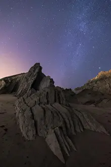 Star Prints: From below of rough cliff peak with colorful blue night sky and shiny stars on background
