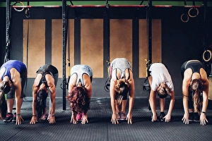 Athleticism Prints: Row of women training in gym, bending forward touching floor