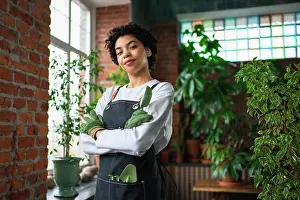 Projects Prints: Running of own business. African woman florist wearing apron in botanical store with green plants