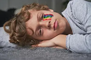 Home Prints: Sad boy with bright rainbow under eye lying on pillow and blanket