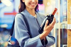Purchase Prints: sale, shopping, consumerism and people concept - happy young woman choosing and buying wine in market or liquor store