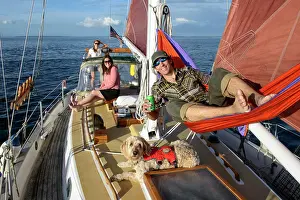 Model Release Prints: San Juan Islands, WA. Man in hammock on deck of Westsail sailboat (with goldendoodle dog and two women)