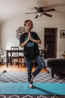 Gradeschooler Prints: School-age boy doing yoga in living room during isolation